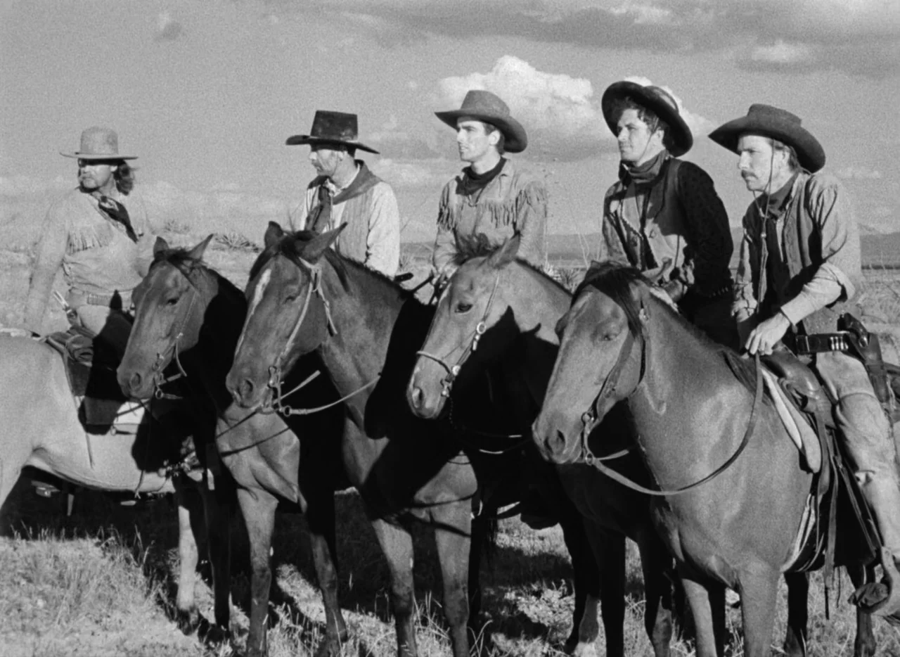 Red River (1948) movie still: fullbody — Five men ride horses in a row across a desolate, sunlit prairie. The men wear period-appropriate Western…