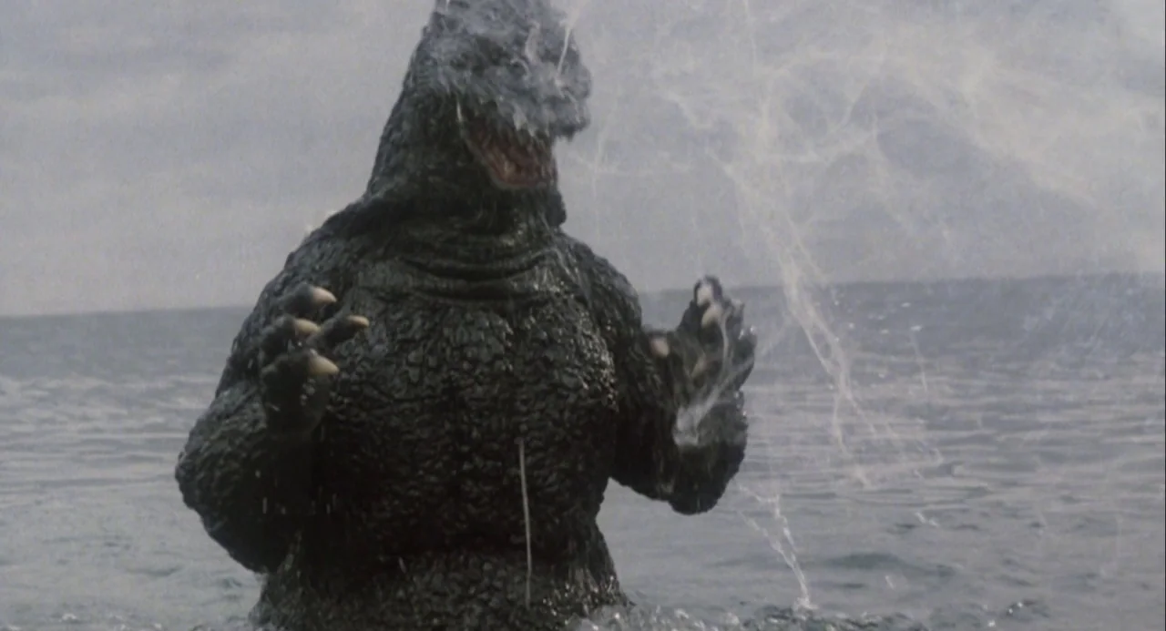 Godzilla and Mothra: The Battle for Earth (1992) movie still: fullbody — A gargantuan reptilian monster stands chest-deep in a choppy, grey ocean…