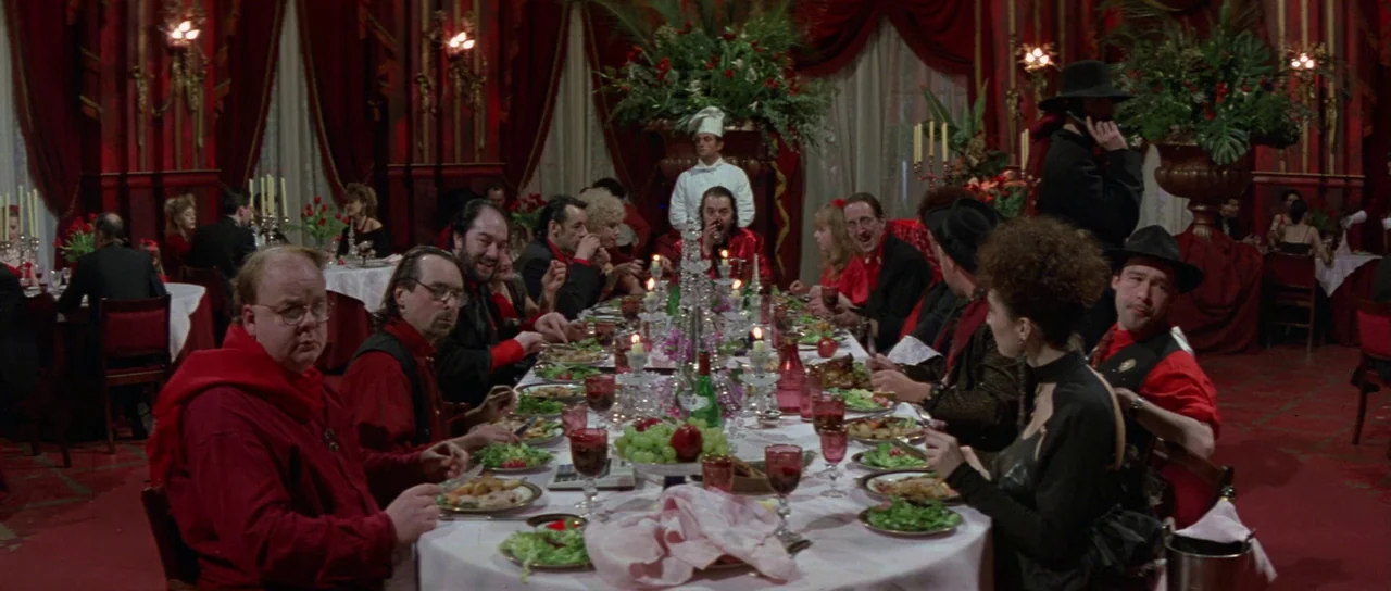 The Cook, The Thief, His Wife & Her Lover (1989) movie still: wide — A long banquet table set with food and candles fills a large, red-walled room.…