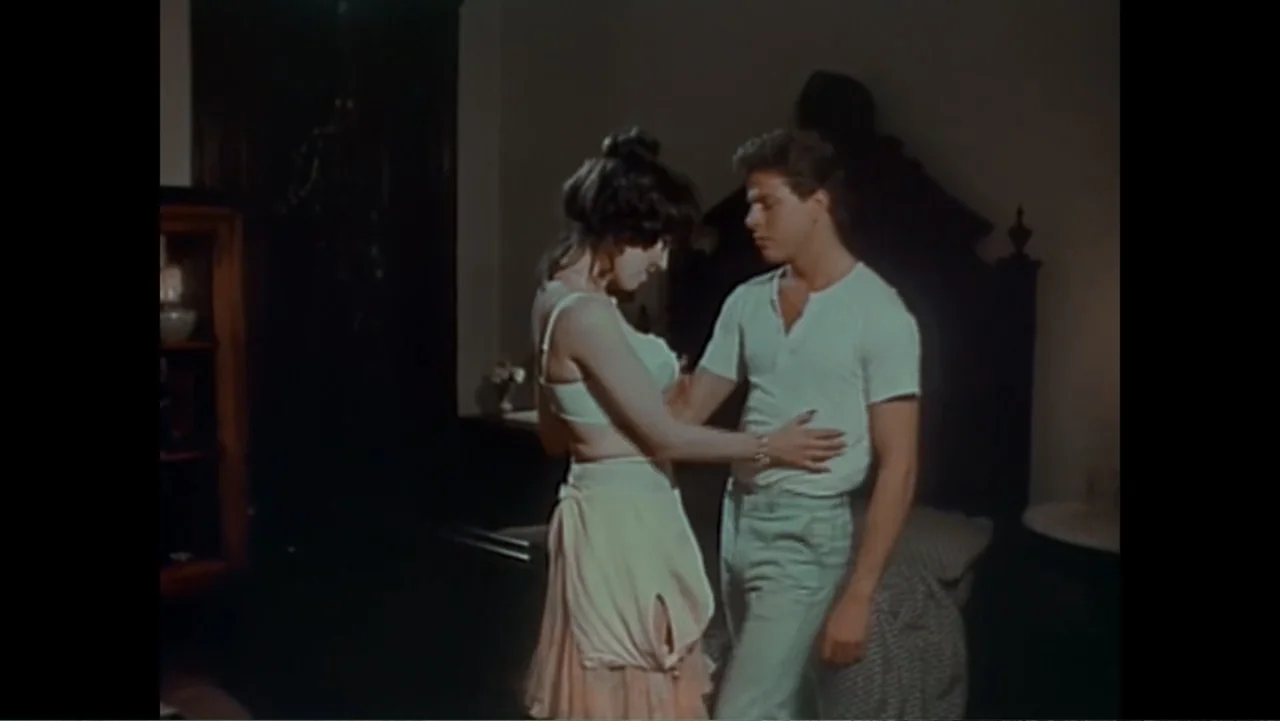 Dear Ms.: A Revolution in Print (2025) movie still: medium — A dimly lit bedroom features a dark wooden headboard and a glass-fronted cabinet. A…