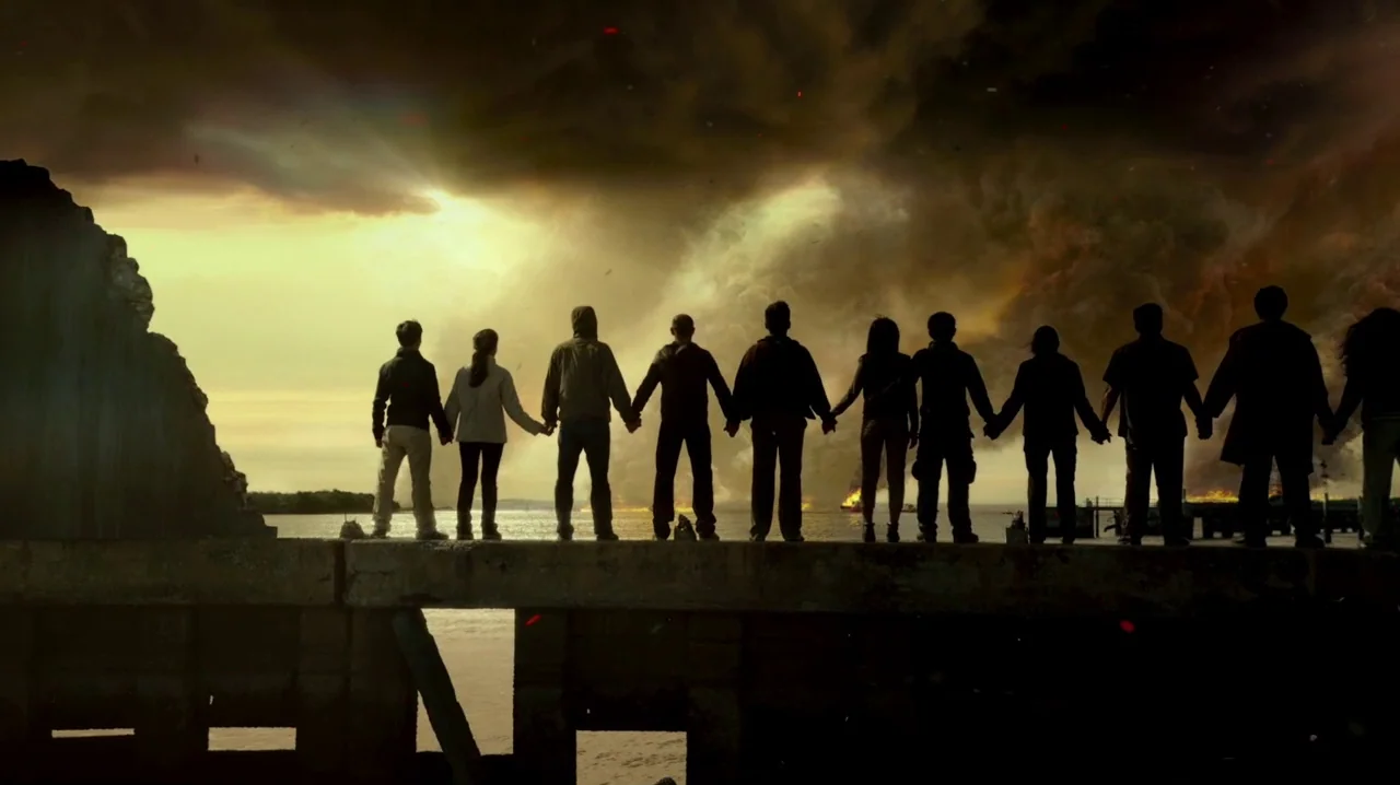 Pacific Rim (2013) movie still: wide — A concrete pier extends into the water against a chaotic, fire-ravaged sky. Ten people stand in a line on the…