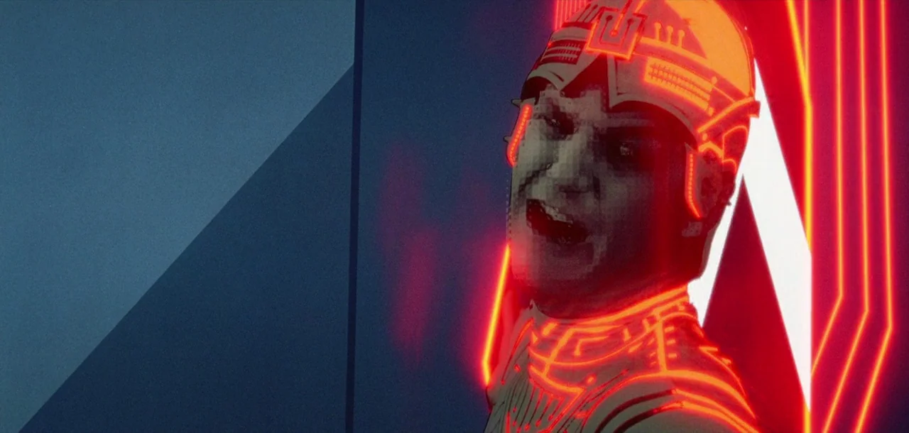 Tron (1982) movie still: closeup — A dark digital environment contains a man wearing a glowing neon suit. The subject stands before a bright red…