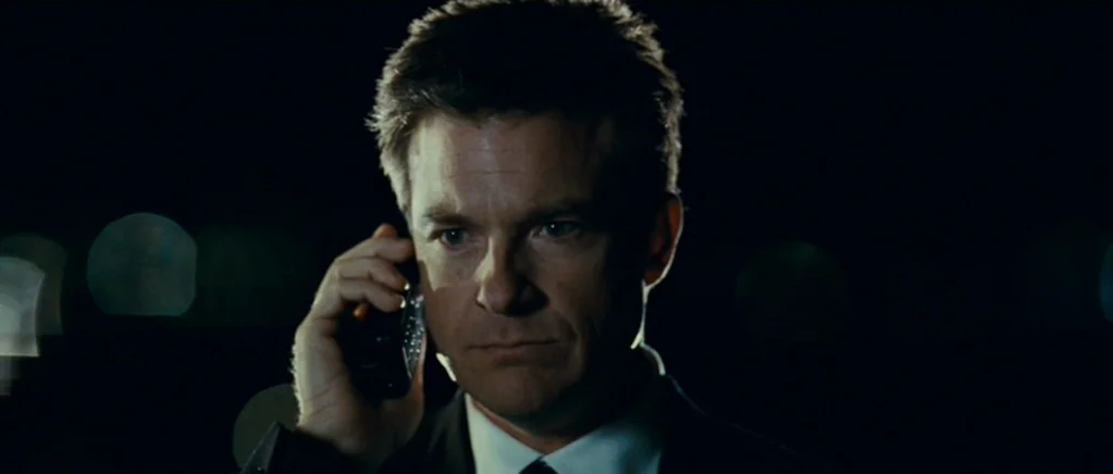 Paul (2011) movie still: closeup — A man in a suit stands outside at night against a dark backdrop. He is speaking on a black mobile phone.