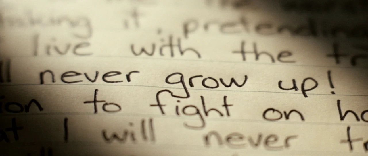 Daybreakers (2009) movie still: closeup — A close-up shot of lined paper features handwritten cursive text in dark ink. The phrase never grow up…