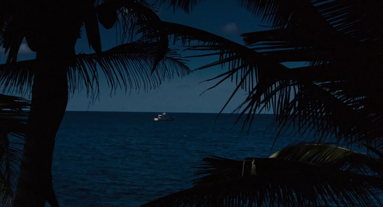 Live and Let Die (1973) movie still: wide — A dark, deep blue ocean stretches to the horizon under a night sky. A small boat sits at the center of…