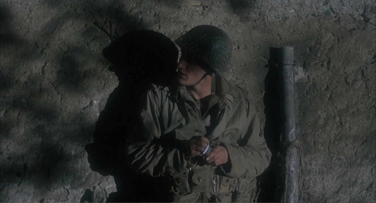 Zone Troopers (1985) movie still: medium — A soldier leans against a crumbling, textured concrete wall in the daylight. He wears World War II…
