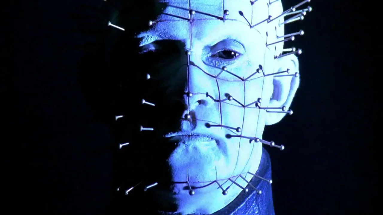 Hellraiser: Bloodline (1996) movie still: closeup — A dark, featureless void surrounds a pale head covered in metallic pins. The figure maintains a…