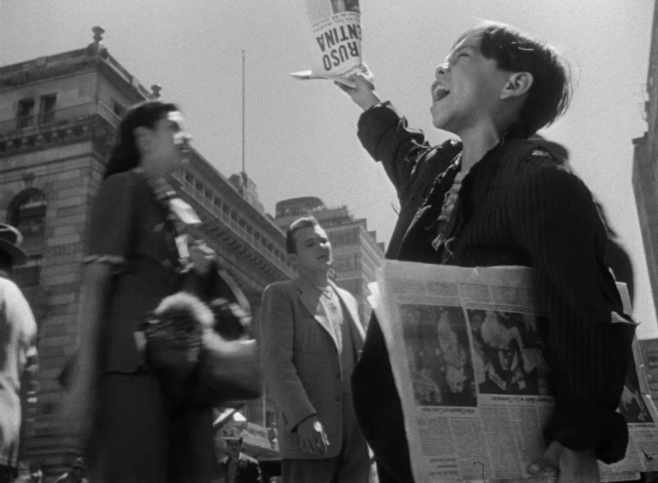 Victims of Sin (1951) movie still: medium — A bustling urban street with ornate 1940s-style stone architecture looming in the background. A young…