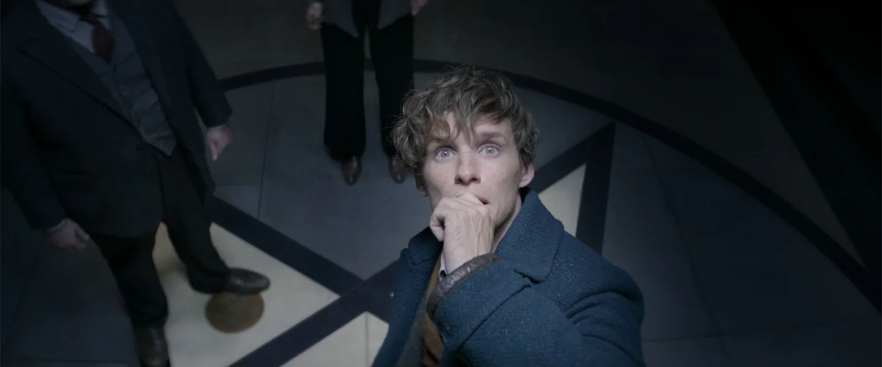 Fantastic Beasts and Where to Find Them (2016) movie still: medium — A dark stone rotunda features a geometric pattern on the floor. A man in a wool…