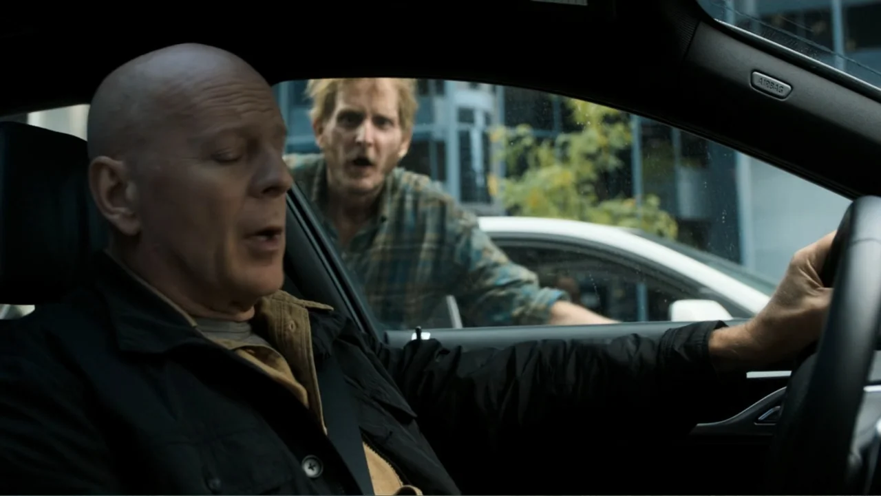 Death Wish (2018) movie still: medium — A dark car interior with a bald driver and a man looking inside. A man with messy hair and a flannel shirt…