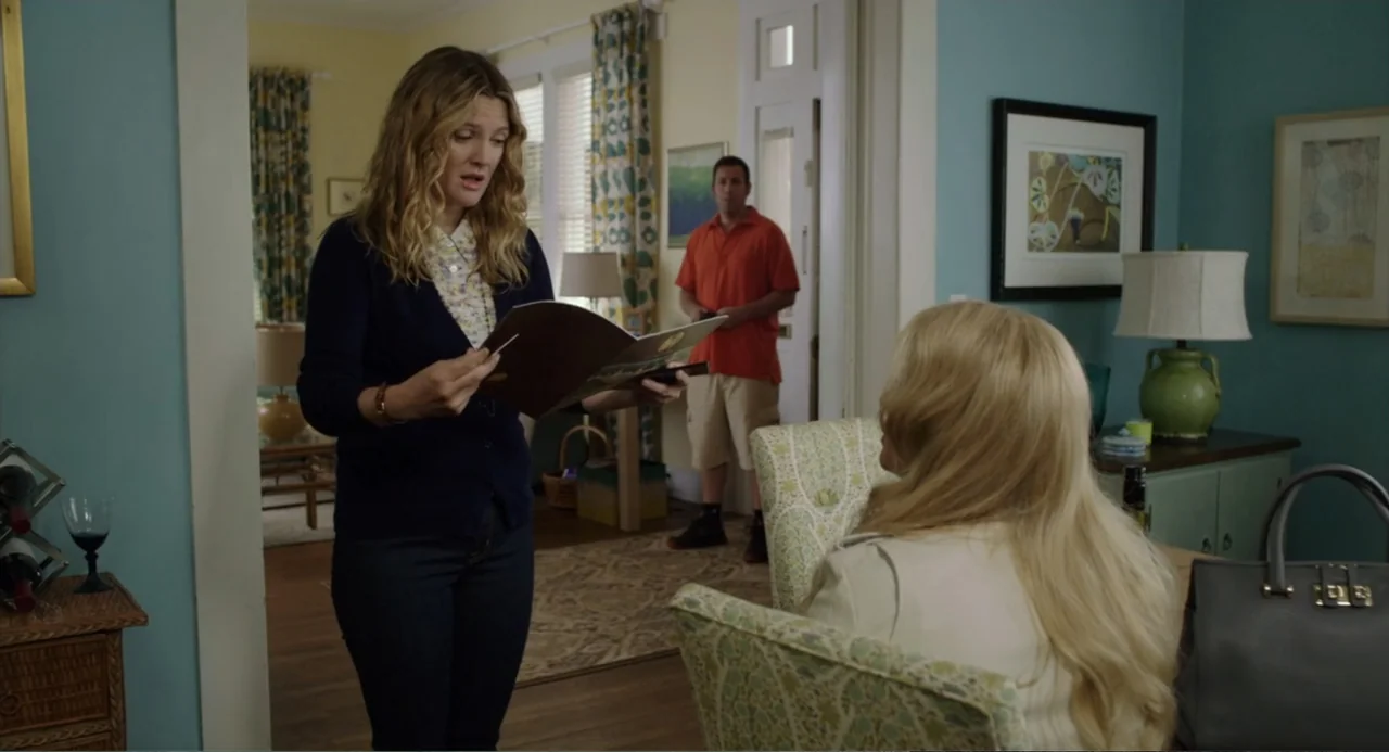 Blended (2014) movie still: medium — A living room features light blue walls, floral curtains, and a patterned armchair. One woman presents a…