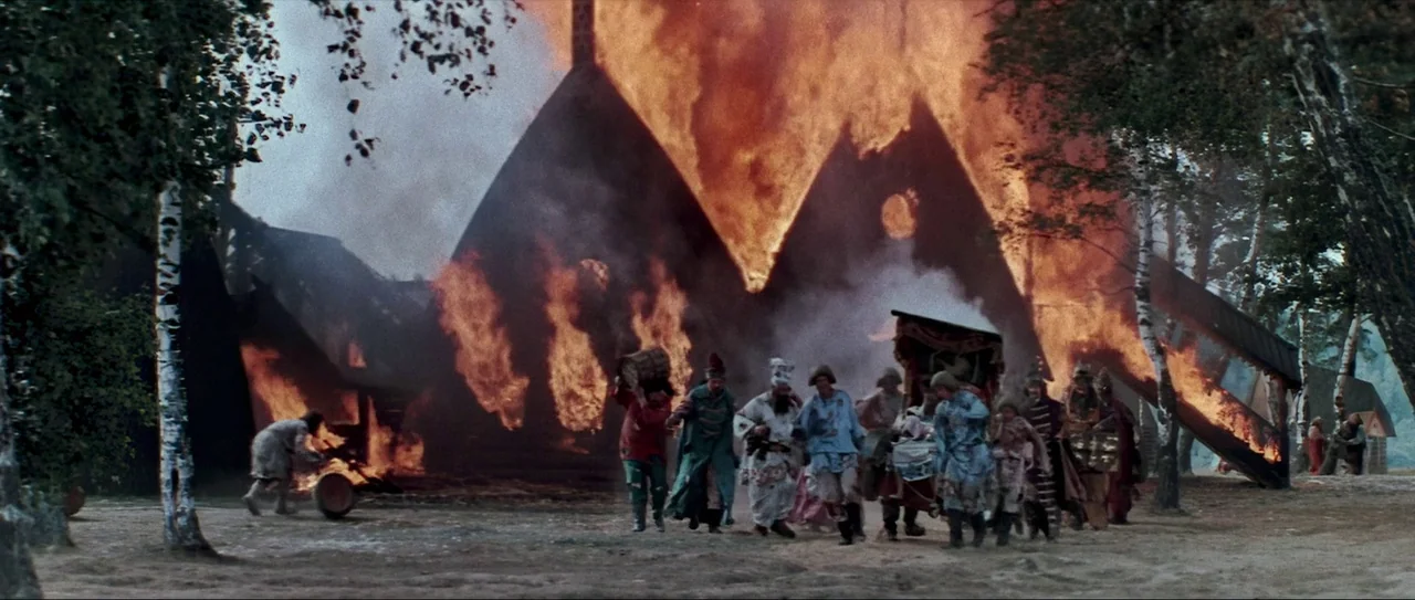 Through Fire, Water and… Brass Pipes (1968) movie still: wide — A group of people in historical clothing evacuates as a wooden building is ablaze.…