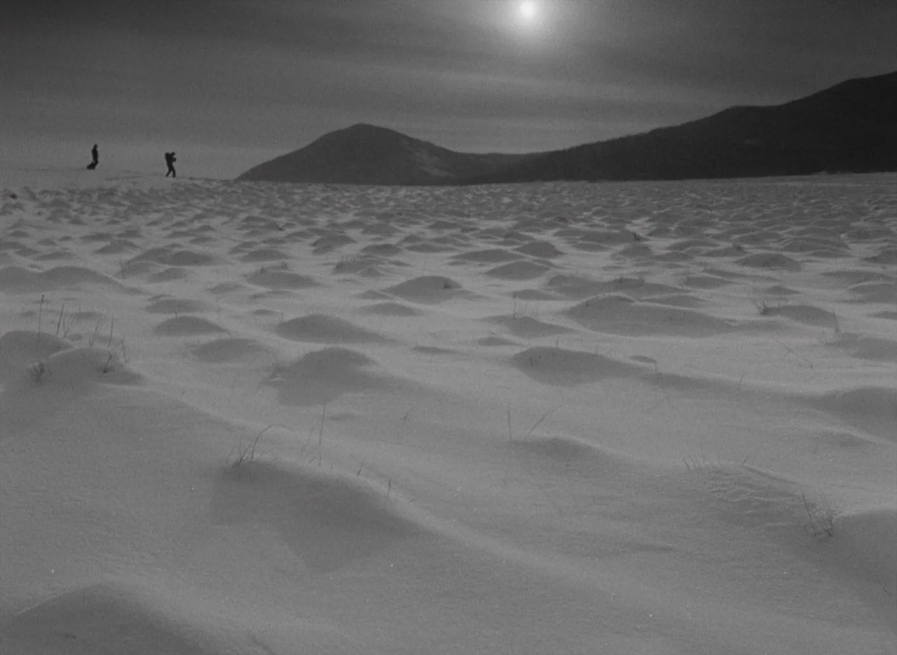 Letter Never Sent (1960) movie still: wide — A vast, undulating expanse of snow-covered terrain extends toward a distant mountain range. Two…