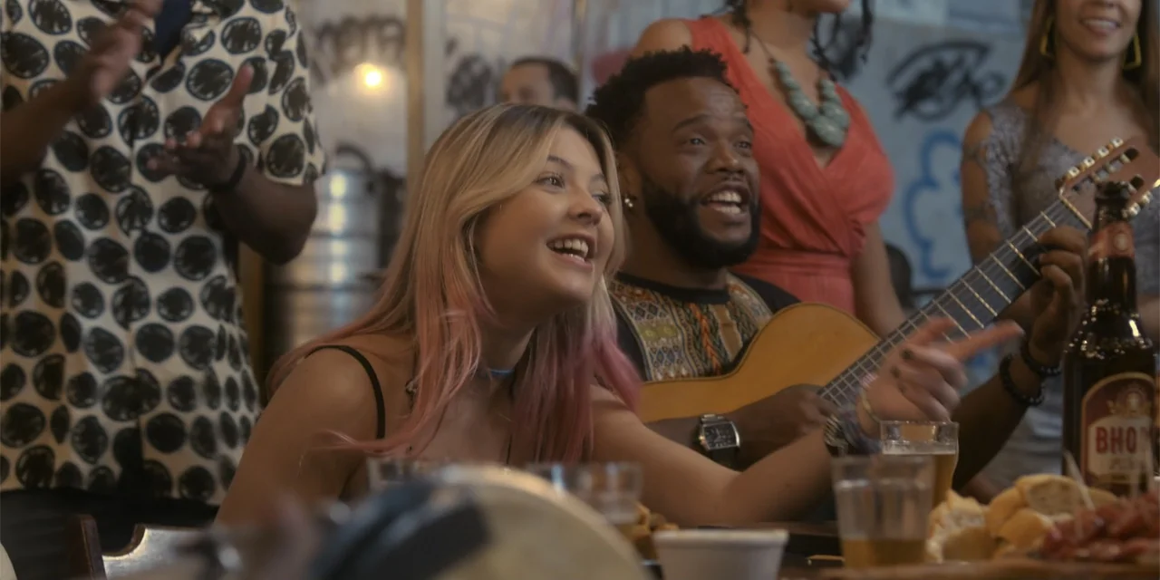An Unforgettable Year - Summer (2023) movie still: medium — A crowded social setting features people gathered around a table with drinks and snacks.…