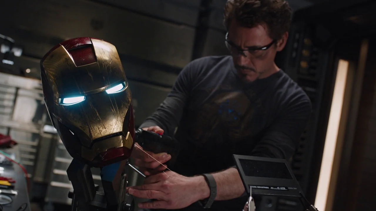 The Avengers (2012) movie still: medium — A cluttered workshop with mechanical components and tools on the work surface. A man focuses intensely…