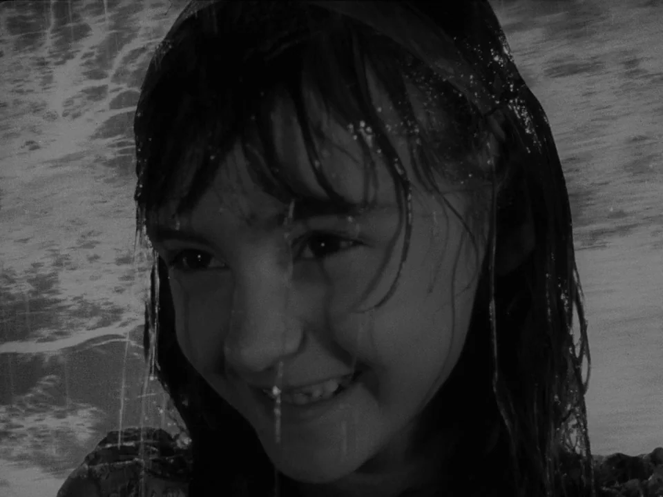 Ivan’s Childhood (1962) movie still: closeup — A close-up shot on a sandy beach under bright daylight. A young girl's face is wet with water…