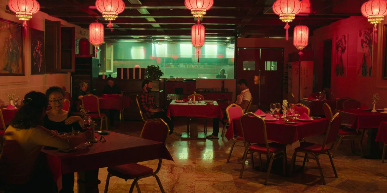 Sniper: G.R.I.T. (2023) movie still: wide — An empty dining room is decorated with red lanterns and set with red tablecloths. A bright, clinical…