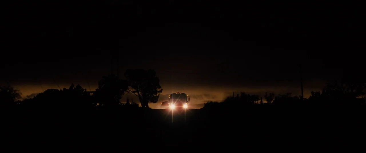 Midnight Special (2016) movie still: wide — A dark, silhouette-heavy road scene at night shows the horizon line under a dark sky. A bus travels…