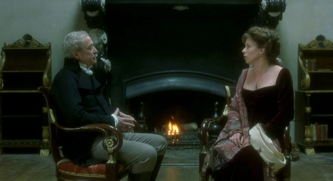 Quills (2000) movie still: medium — An opulent 19th-century room features a grand black fireplace and antique wooden furniture. A man and a woman…