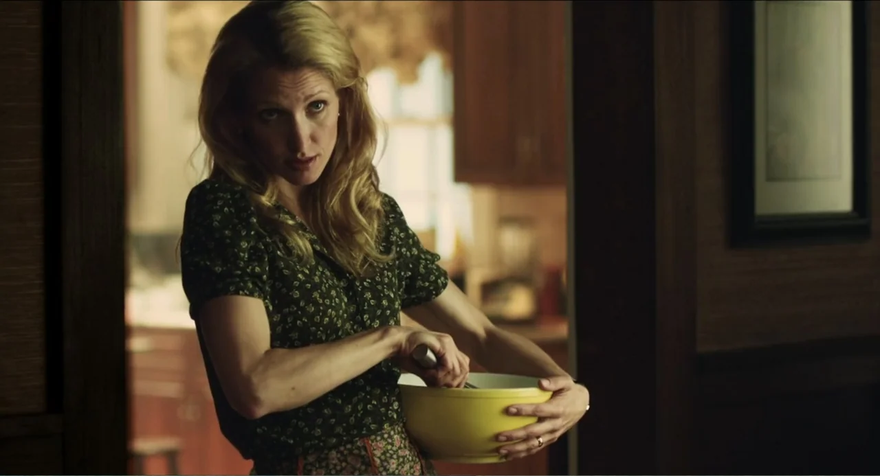 Haunter (2013) movie still: medium — A woman stands in a home interior doorway holding a yellow mixing bowl. She whisks the contents inside the bowl…