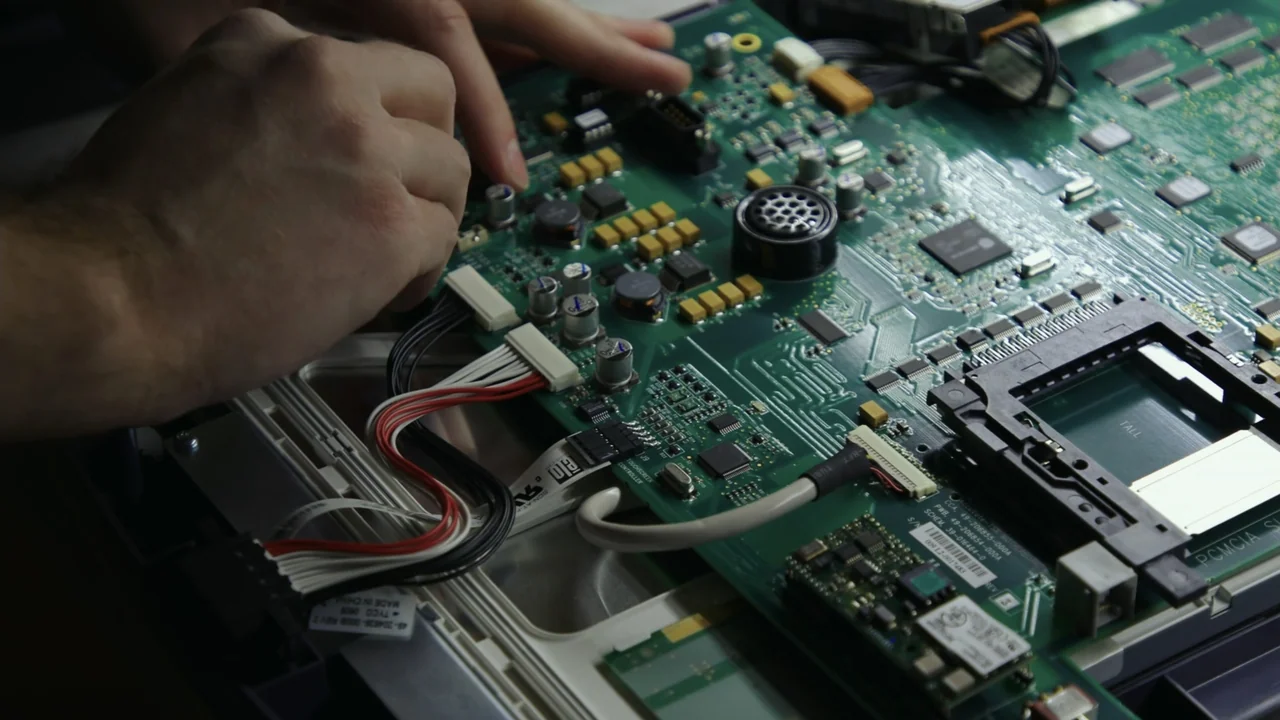 Kill Chain: The Cyber War on America's Elections (2020) movie still: closeup — An open electronic device rests on a surface with its complex green…