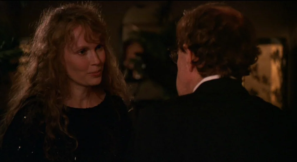Crimes and Misdemeanors (1989) movie still: medium — A dimly lit indoor space with blurred furniture and dark shadows in the background. A man in a…