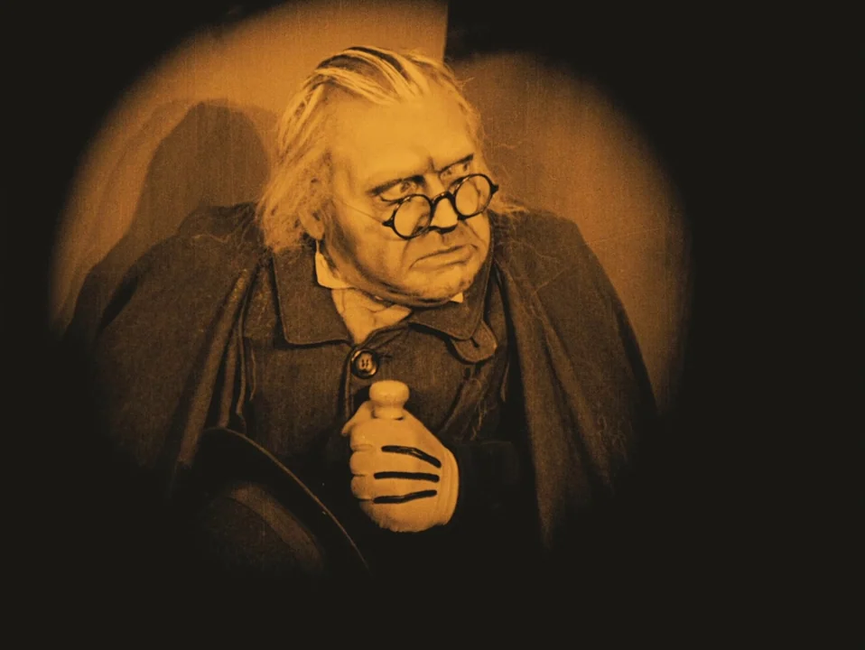 The Cabinet of Dr. Caligari (1920) movie still: medium — An elderly man is framed within a dark circular vignette. He holds a cane while looking off…