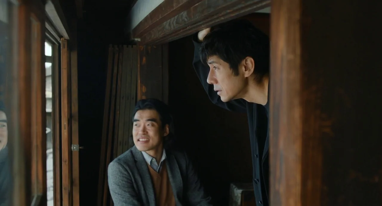 Drive My Car (2021) movie still: medium — The interior of a traditional house features dark wooden architectural framing and sliding walls. Two men…
