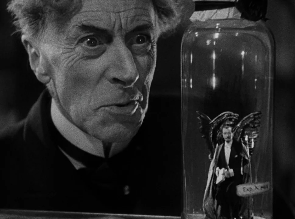 The Bride of Frankenstein (1935) movie still: medium — A dark laboratory features an elderly man leaning toward a large glass jar. Inside the glass…