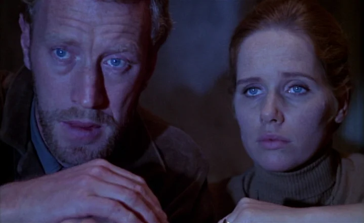 The Passion of Anna (1969) movie still: medium — Two individuals sit together in a dimly lit, nondescript room. The man and woman look forward with…