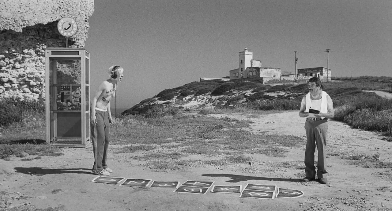 The Legend Of Kaspar Hauser (2012) movie still: wide — A desolate clifftop landscape features a phone booth and a drawn hopscotch grid. A young man…