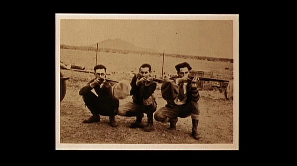 Bonnie And Clyde (1967) movie still: fullbody — Three men crouch in an open field against a backdrop of distant hills. Each man aims a rifle forward…