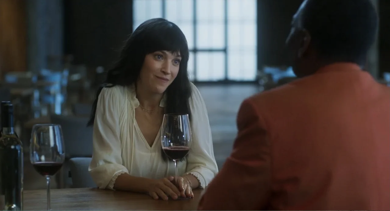 Message in a Bottle (1999) movie still: medium — A modern restaurant interior with tables and a large window in the background. A woman in a white…