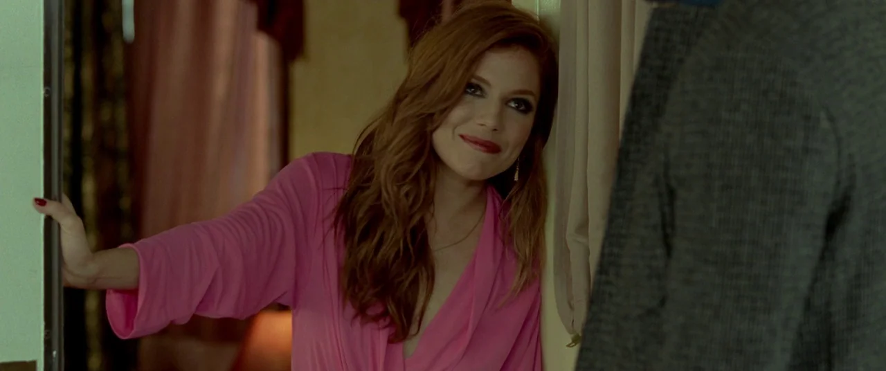 Mississippi Grind (2015) movie still: medium — A woman stands in a doorway with beige walls and soft-focus window curtains nearby. She leans against…