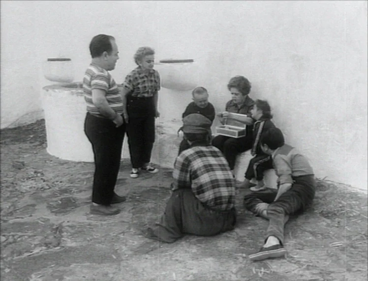 Even Dwarfs Started Small (1970) movie still: fullbody — An outdoor paved courtyard with plain white walls and two circular concrete structures. A…