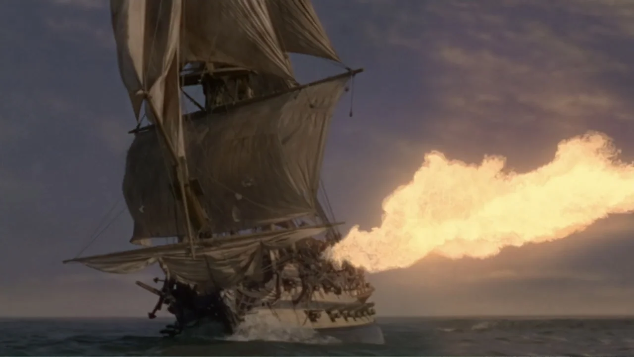 Empire Queen: The Golden Age of Magic (2024) movie still: wide — A wooden sailing ship moves through choppy open water during a golden hour sunset.…