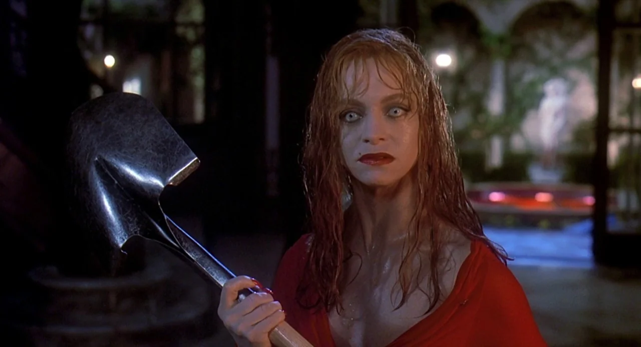 Death Becomes Her (1992) movie still: medium — A stone courtyard features a central fountain area visible in the blurred background. A woman with…