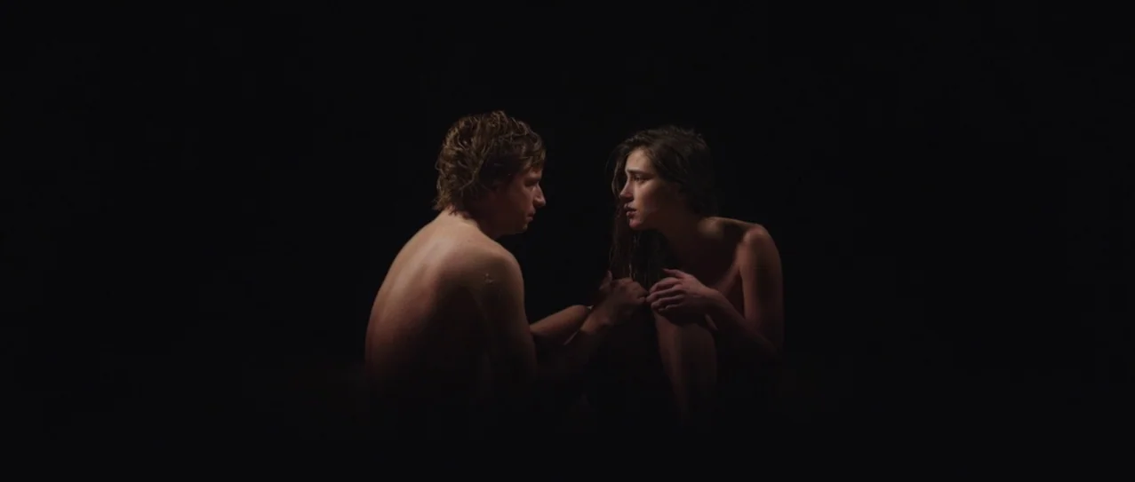 Vanishing Waves (2012) movie still: medium — A man and a woman sit facing each other in a pitch-black void. The subjects appear to be unclothed and…
