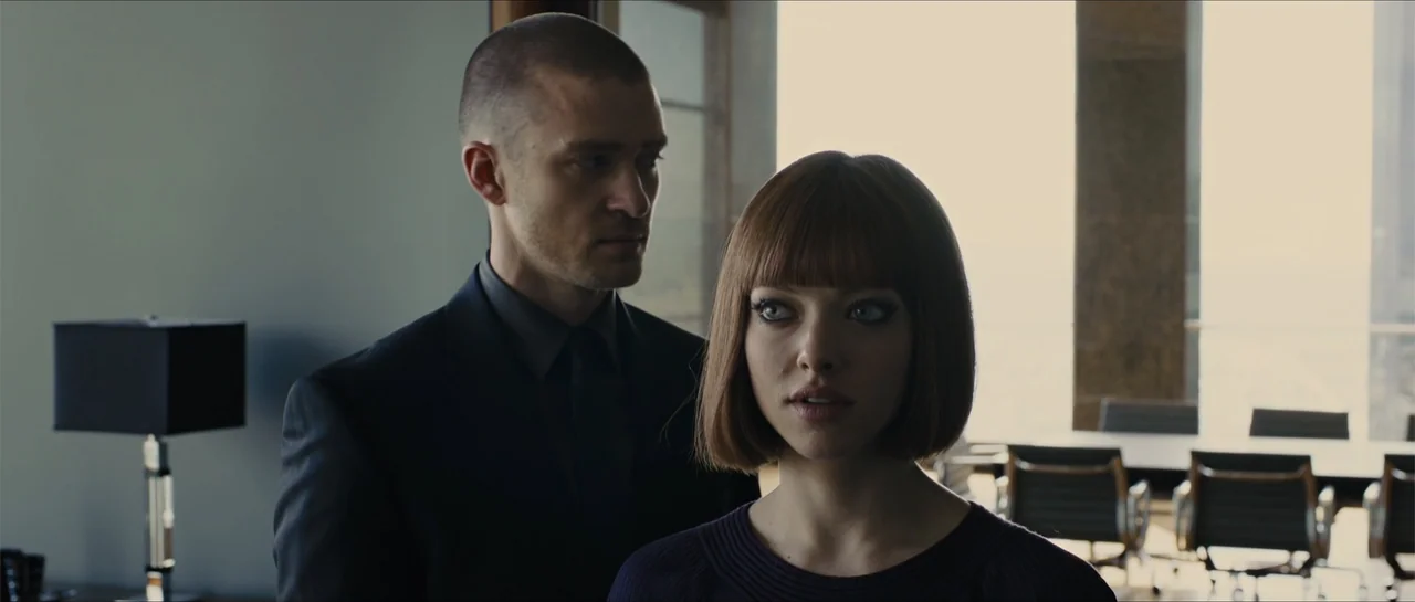 In Time (2011) movie still: medium — A high-rise executive office features floor-to-ceiling windows and modern conference room furniture. A man in a…