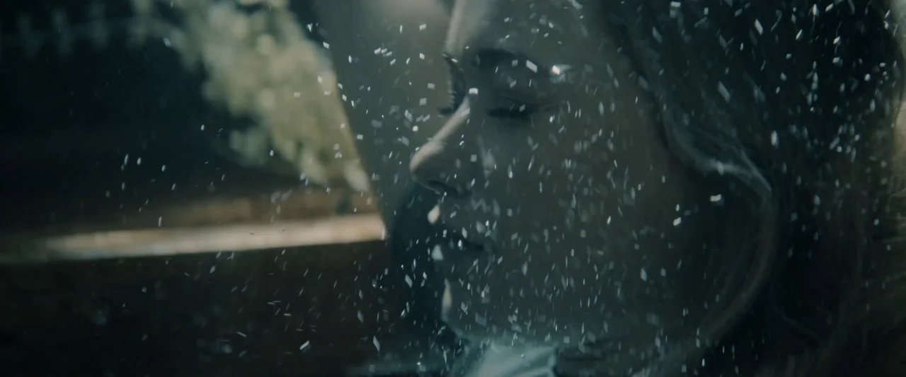 Great White (1998) movie still: closeup — A dark outdoor space at night with light reflecting off falling snow particles. A woman stands in profile…