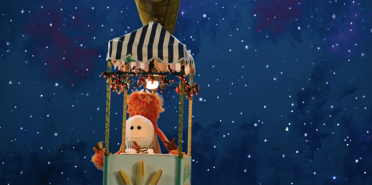 31 Minutes: One Hot Christmas (2025) movie still: medium — A puppet basket with a striped canopy floats against a deep blue starry sky. A white…