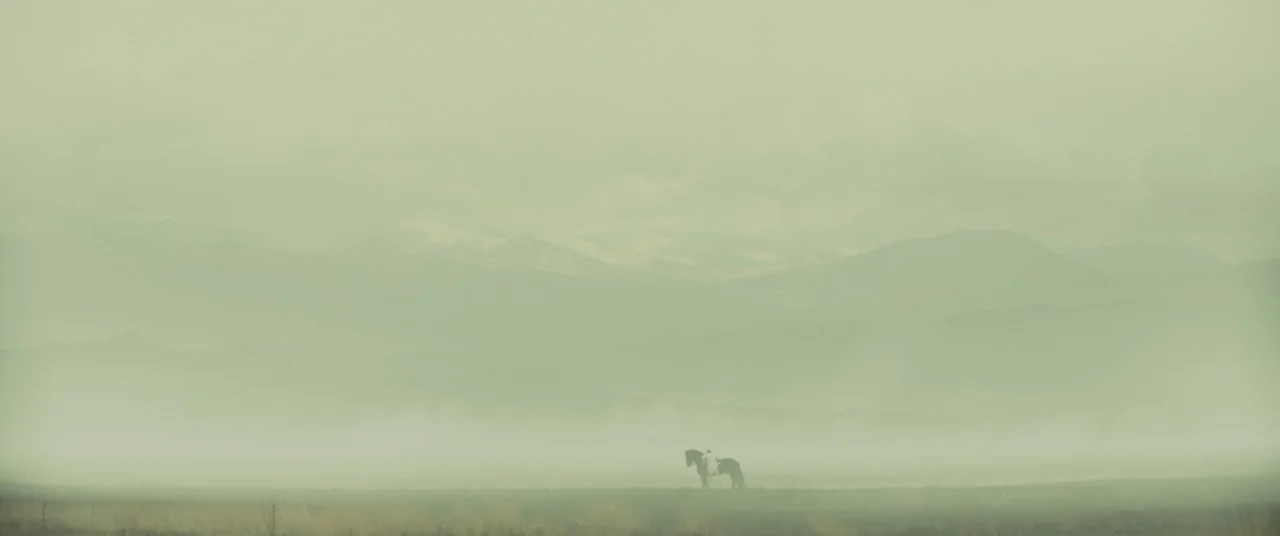 Macbeth (2015) movie still: wide — A vast, flat landscape is obscured by a thick blanket of morning mist. A lone rider on horseback stands…
