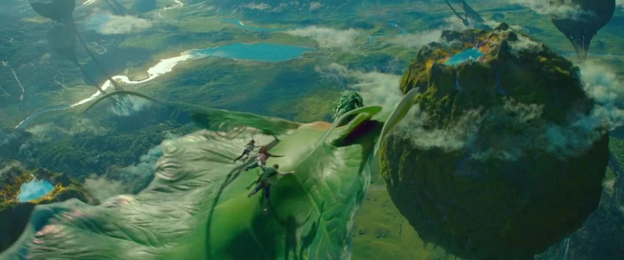 A Wrinkle In Time (2018) movie still: wide — A sprawling aerial view shows massive floating islands over a lush green valley floor. Three small…