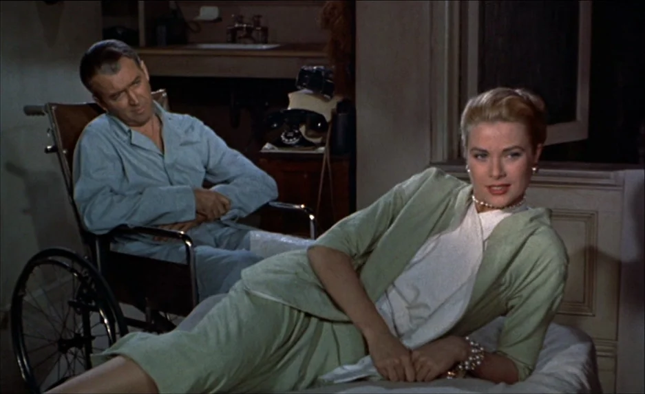 Rear Window (1954) movie still: medium — A 1950s residential space features a sofa near a dark wooden telephone table. A woman lies on the couch…