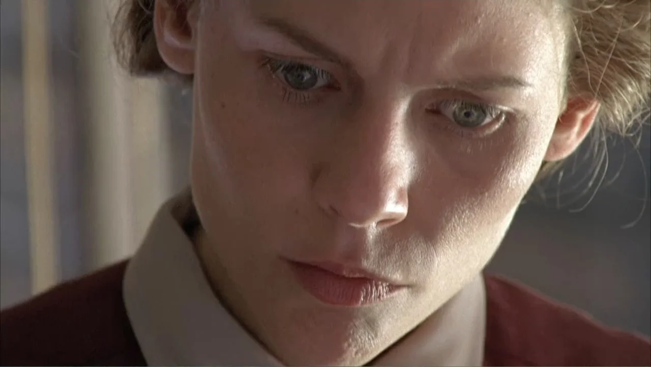 Temple Grandin (2010) movie still: closeup — A close view of a young woman's face indoors near a window. She looks downward with a focused…