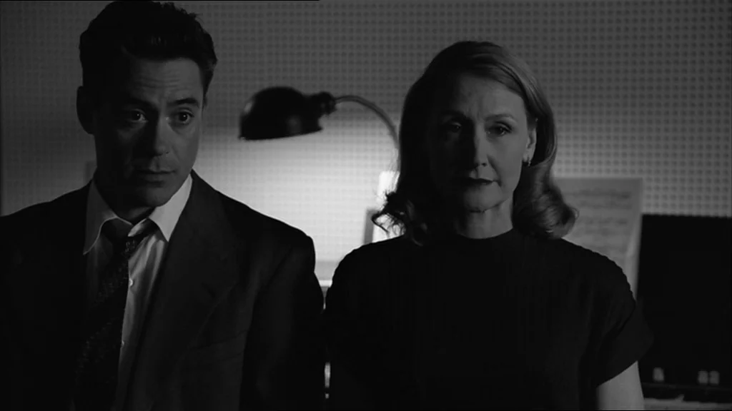 Good Night And Good Luck (2005) movie still: medium — An interior space with a textured white wall background and a metal lamp. A man and a woman…