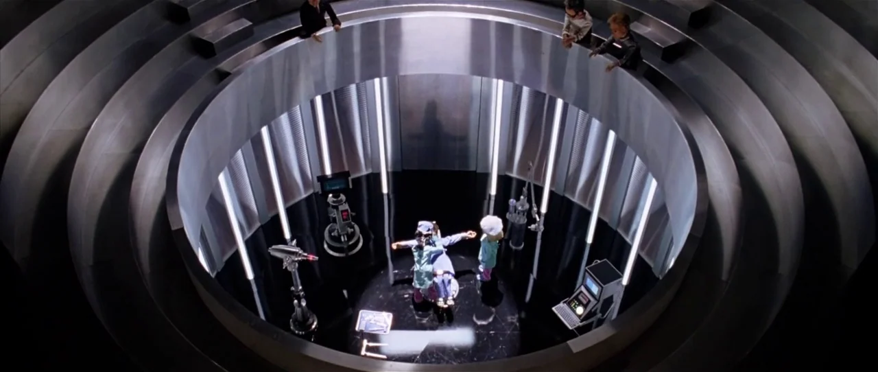 Team America: World Police movie still: wide — A circular, high-tech laboratory features a central metallic floor and observation level above. Two…