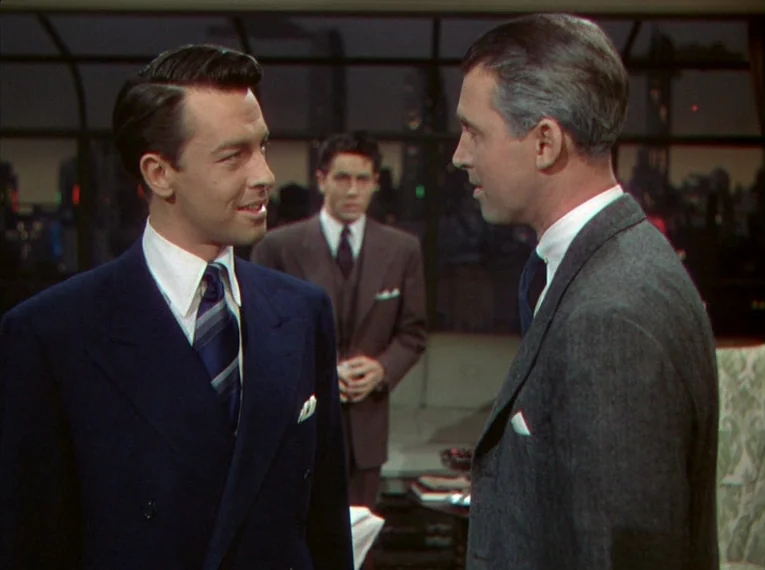 Rope (1948) movie still: medium — An upscale apartment interior at night with large windows showing a distant city skyline. Two men in formal…