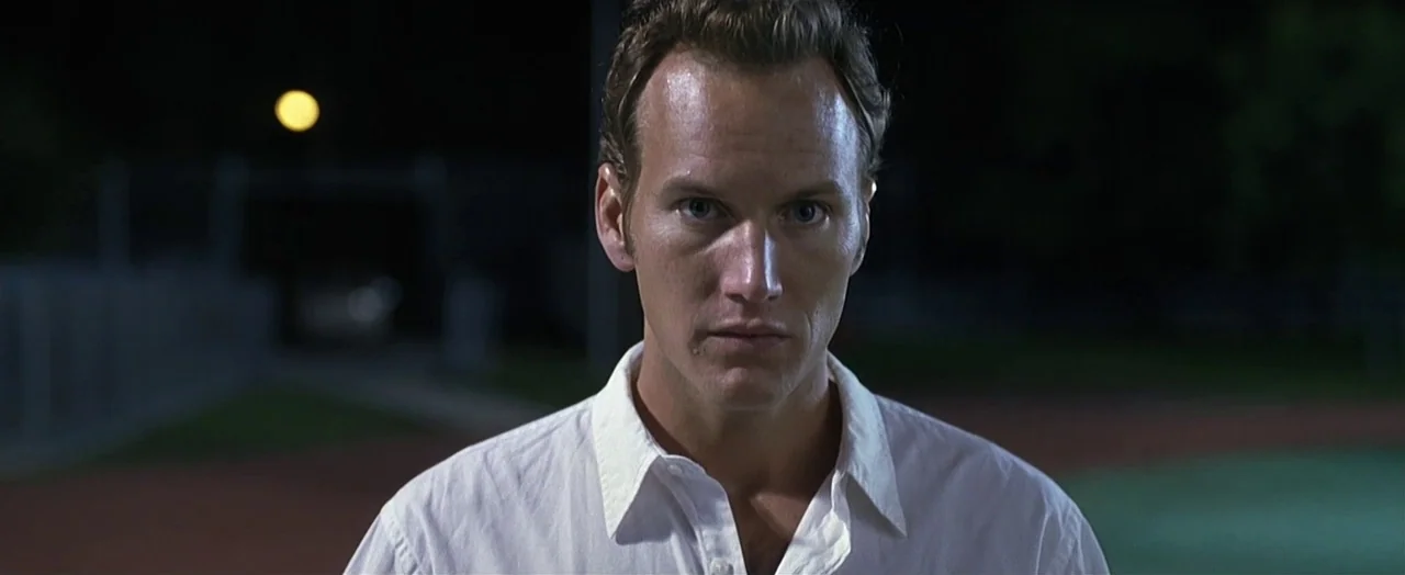 Little Children (2006) movie still: closeup — A man stands outdoors at night on a dark athletic field. The person faces the camera with a neutral…