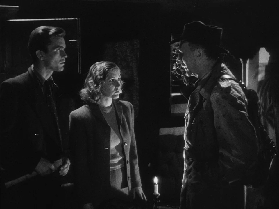 It Rains On Our Love (1946) movie still: medium — A dark room illuminated only by the flickering flame of a small candle. A woman stands in…